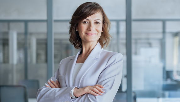 Confident woman in a modern office with arms crossed, with soft graphic shapes overlaid.